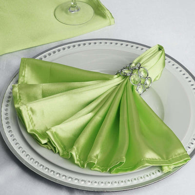 Green satin napkin elegantly folded on a decorative plate with a crystal ring.