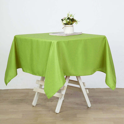 Green tablecloth draped over a wooden table with a floral centerpiece.