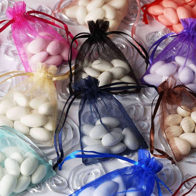 Colorful organza bags with candy-coated almonds on a textured surface.