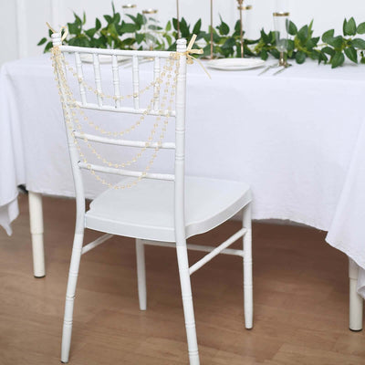 White chair adorned with pearl garland, set for an elegant dining experience.