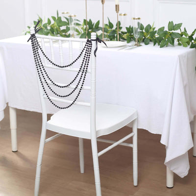 Black beaded chair decoration with greenery for elegant table setting.
