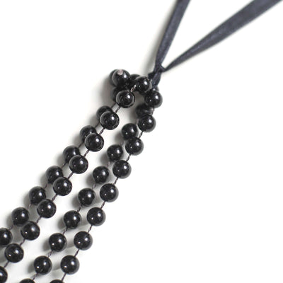Black bead necklace with ribbon closure on a white background