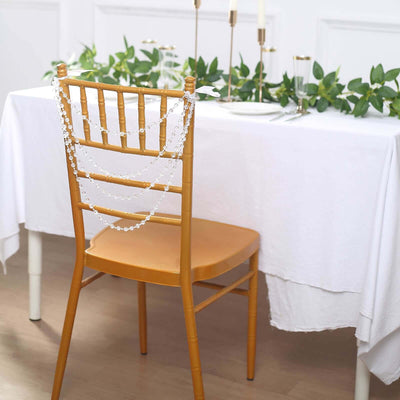 Decorative chair with beaded chains at a dining table adorned with greenery.