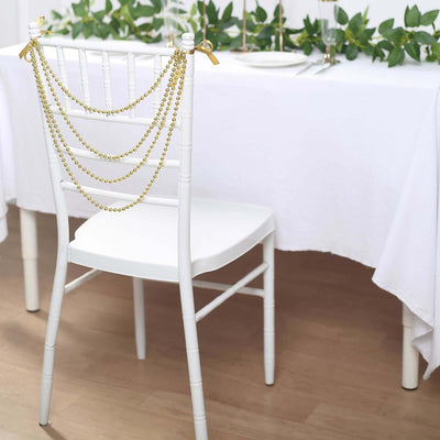 White chair adorned with gold bead garland, set for an elegant dining experience.