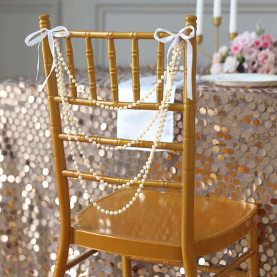 Gold Chiavari chair adorned with pearl beads and ribbons at a decorated table.