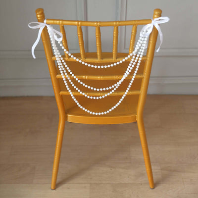 Yellow chair with white beads and ribbons tied on the back.
