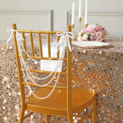 Gold chiavari chair adorned with white pearl garlands at a decorated table.