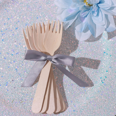 Wooden forks tied with a silver ribbon, styled with a blue flower.