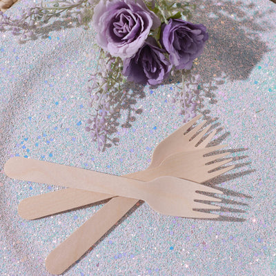 Eco-friendly wooden forks on a glittery surface with flowers.