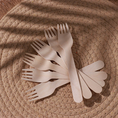 Wooden forks arranged on a woven placemat.