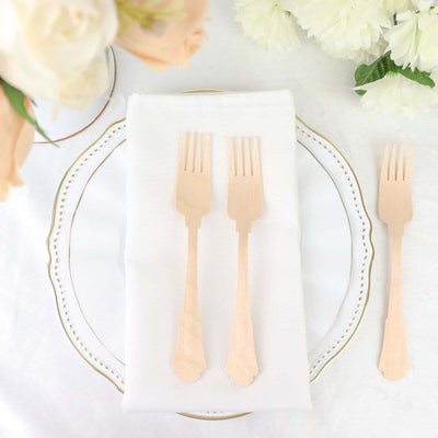 Wooden forks on a white plate with a napkin, surrounded by flowers.