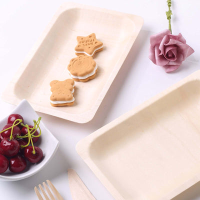 Eco-friendly wooden trays with cookies and cherries on a white background.