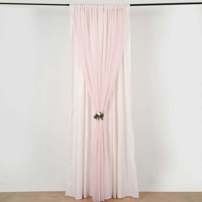 Pink sheer curtain with floral tieback on a plain backdrop.