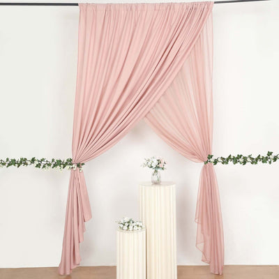Pink drapery backdrop with floral accents and decorative pedestals.