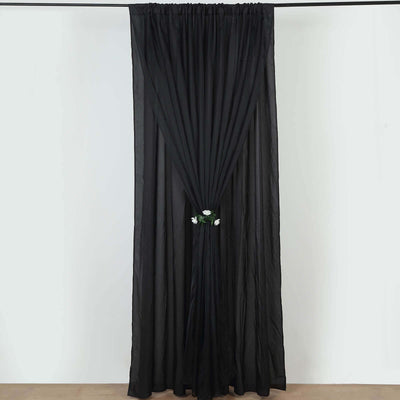 Black sheer curtain with floral tieback hanging elegantly.