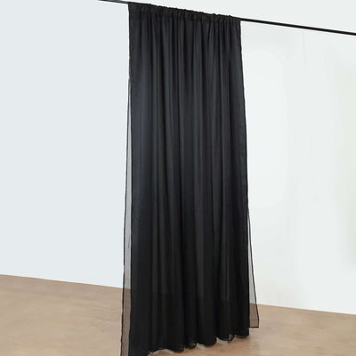 Black sheer curtain hanging from a rod against a plain background