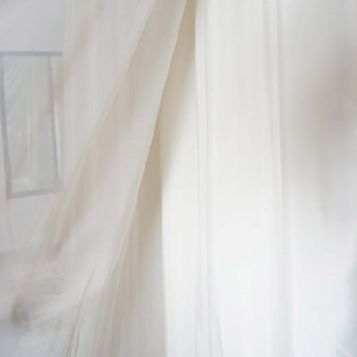 Sheer white fabric gently flowing in soft light.