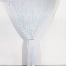 An iridescent blue sequin curtain hanging on a white wall