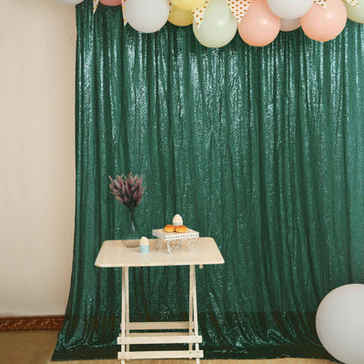 Decorative table with cupcakes against a sparkly green backdrop.