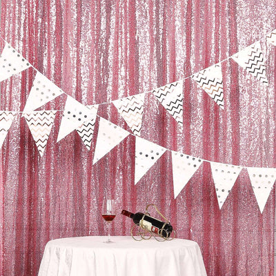 Party decoration with a pink sequin backdrop, banners, and wine on a table.