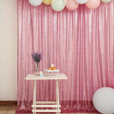 Decorative pink sequin backdrop with balloons and a table for events or photo shoots.