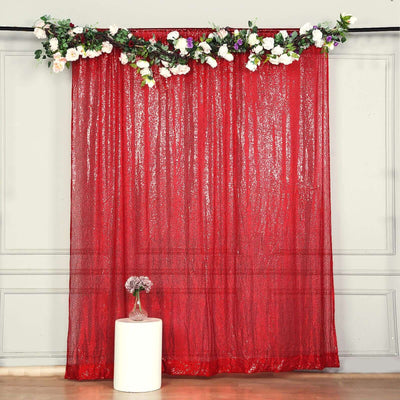 Red sequin curtain with floral garland, styled in a room setting.