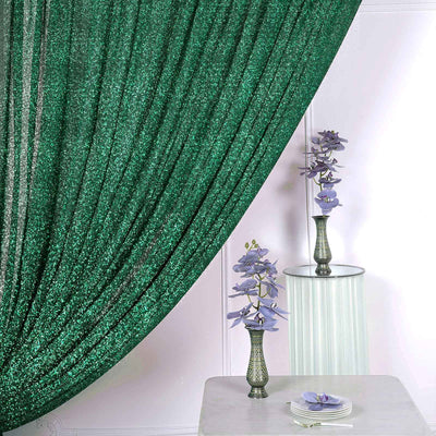 Green sequin curtain with decorative vases and flowers on a table.