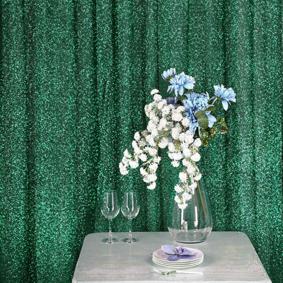 Vase with blue and white flowers on a table with sparkling green backdrop.