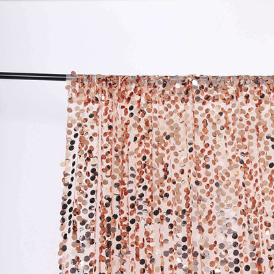 Rose gold sequin curtain hanging on a black rod against a white background.