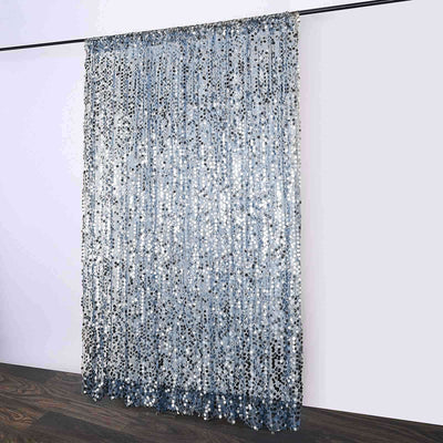Silver sequin curtain hanging on a rod against a plain wall.