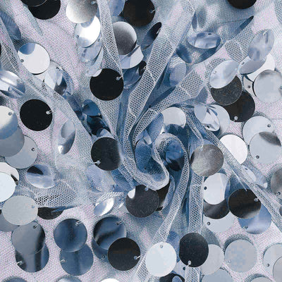 Blue and silver sequins scattered on a light fabric background.