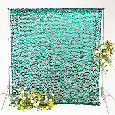 Turquoise sequin backdrop with floral arrangements on each side.