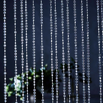 Crystal bead curtain strands with a blurred plant background.