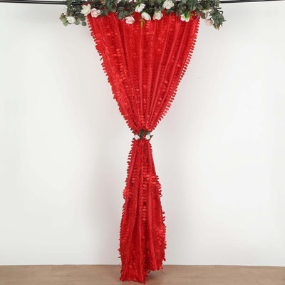 Red ruffled curtain with floral accents hanging from a rod.
