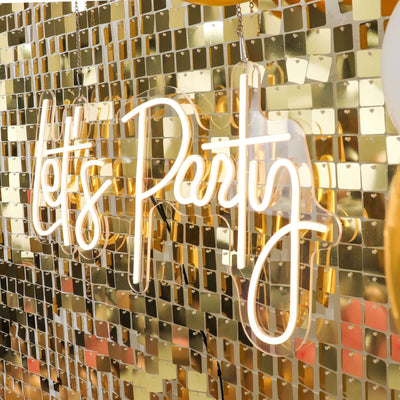Neon "Let's Party" sign against a golden backdrop.