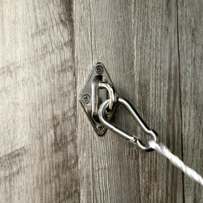 Metal wall anchor with carabiner and rope on textured wooden background.