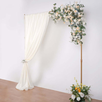Floral wedding arch with draped fabric and colorful flowers arrangement.