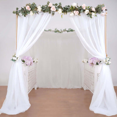 Elegant floral wedding arch with draped fabric and decorative flowers.
