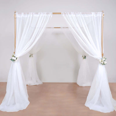 White draped wedding arch with floral accents on a light background.
