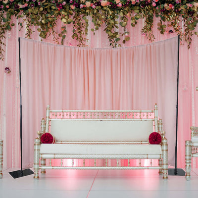 Elegant white sofa with decorative accents against a pink backdrop.