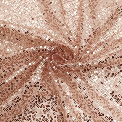 Rose gold sequin fabric with shimmering texture in a spiral pattern.