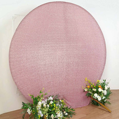 Pink glitter backdrop with floral arrangements in front.