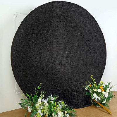 Black round backdrop with floral arrangements on the sides.
