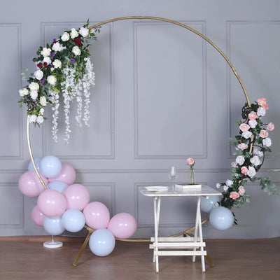 Decorative floral arch with balloons and table for events or photo shoots.