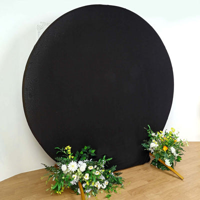 Black circular backdrop with floral arrangements on either side.