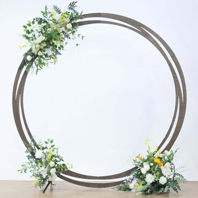 Decorative floral circle frame with greenery and flowers on a plain backdrop.