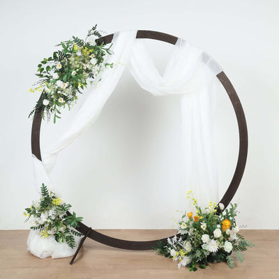 Floral arch decoration with draped fabric and greenery on a plain background.