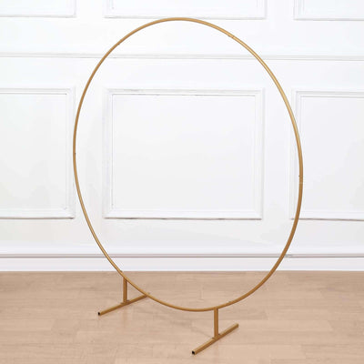 Gold circular photo backdrop stand on a plain surface.