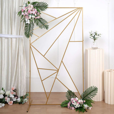 Geometric gold photo backdrop with floral accents and greenery.