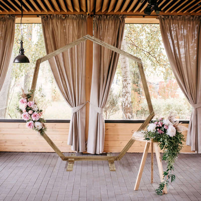 Wooden hexagon frame with flowers in a decorated indoor venue setting.